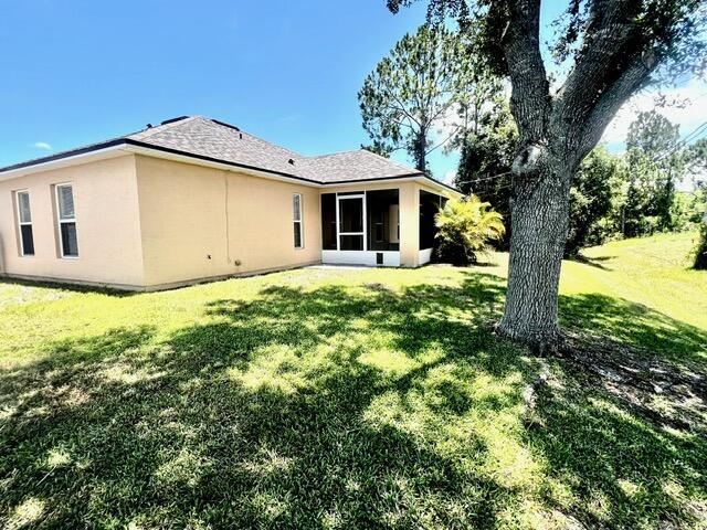 8065 99th Ct, Vero Beach, FL 32967 - rear view of property with a yard, a sunroom, and stucco siding
