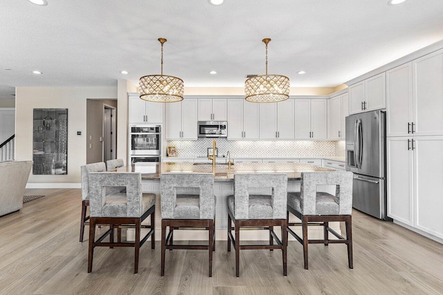 9657 Sterling Shores St, Delray Beach, FL 33446 - kitchen with appliances with stainless steel finishes, light wood finished floors, a sink, decorative backsplash, and decorative light fixtures