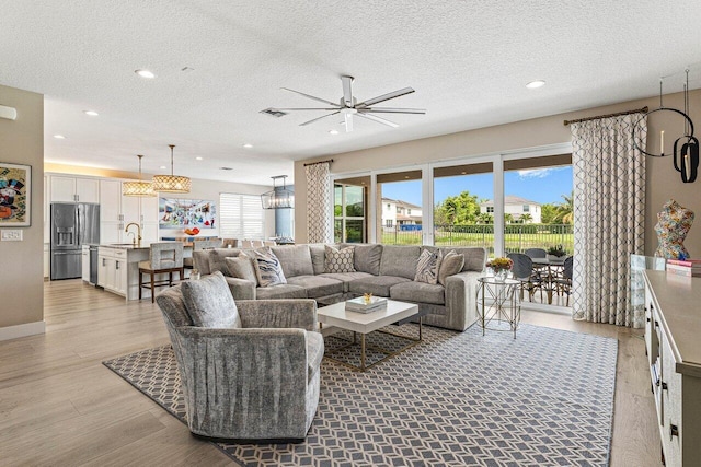 9657 Sterling Shores St, Delray Beach, FL 33446 - living room featuring light wood finished floors, ceiling fan, a textured ceiling, recessed lighting, and a chandelier