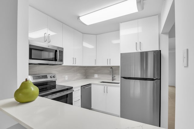 175 Fanshaw E Unit 175, Boca Raton, FL 33434 - kitchen featuring stainless steel appliances, a sink, light countertops, white cabinets, and decorative backsplash