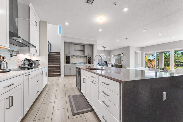 9258 Greenspire Ln, Lake Worth, FL 33467 - kitchen with wall chimney range hood, a sink, black electric cooktop, a large island with sink, and stainless steel dishwasher