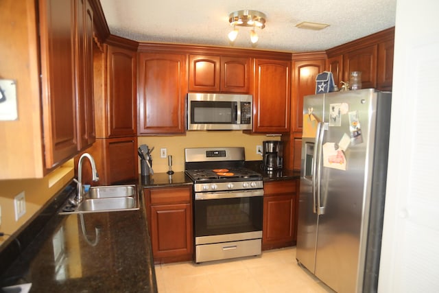 864 SE Tierra Ct, Port Saint Lucie, FL 34983 - kitchen with stainless steel appliances, a sink, light tile patterned flooring, a textured ceiling, and dark stone counters