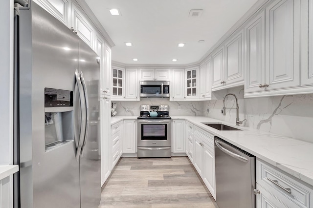 2701 N Ocean Blvd Unit E205, Boca Raton, FL 33431 - kitchen with appliances with stainless steel finishes, a sink, light wood-type flooring, white cabinetry, and recessed lighting