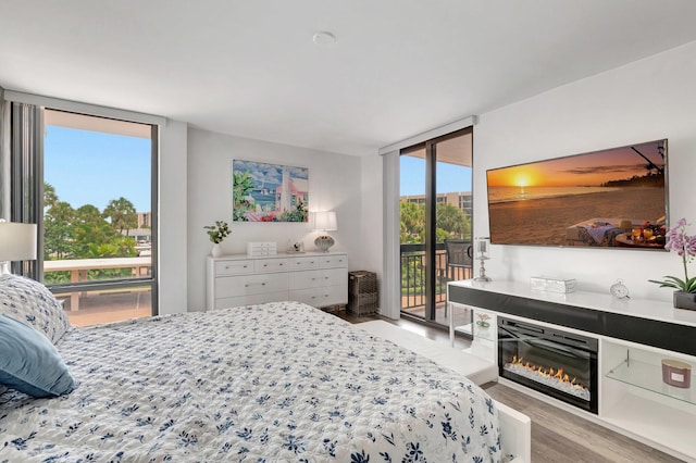 2701 N Ocean Blvd Unit E205, Boca Raton, FL 33431 - bedroom with access to exterior, expansive windows, light wood-type flooring, and a glass covered fireplace