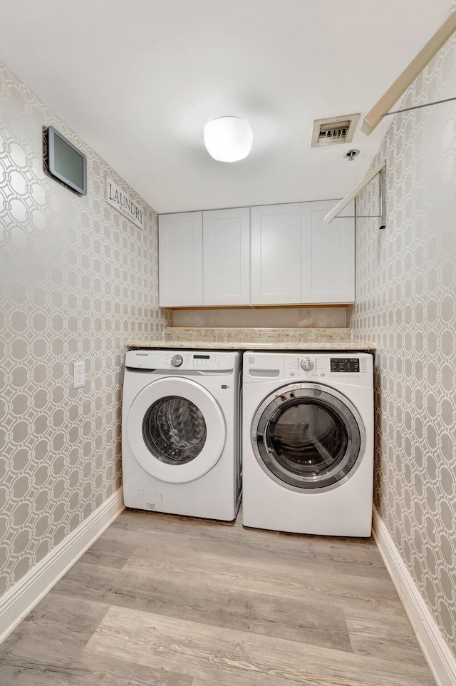 2701 N Ocean Blvd Unit E205, Boca Raton, FL 33431 - laundry area featuring wallpapered walls, washing machine and clothes dryer, light wood-style floors, baseboards, and cabinet space