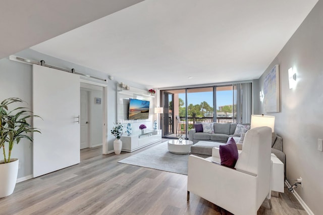 2701 N Ocean Blvd Unit E205, Boca Raton, FL 33431 - living room featuring a barn door, wood finished floors, baseboards, and a wall of windows