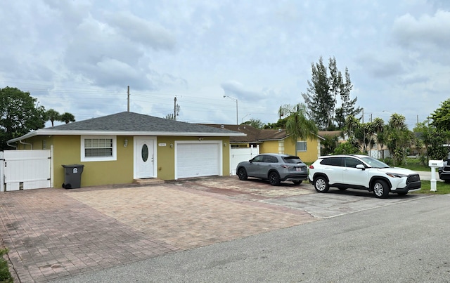 5692 Coconut Rd, West Palm Beach, FL 33413 - view of front of home with decorative driveway, an attached garage, stucco siding, roof with shingles, and a gate