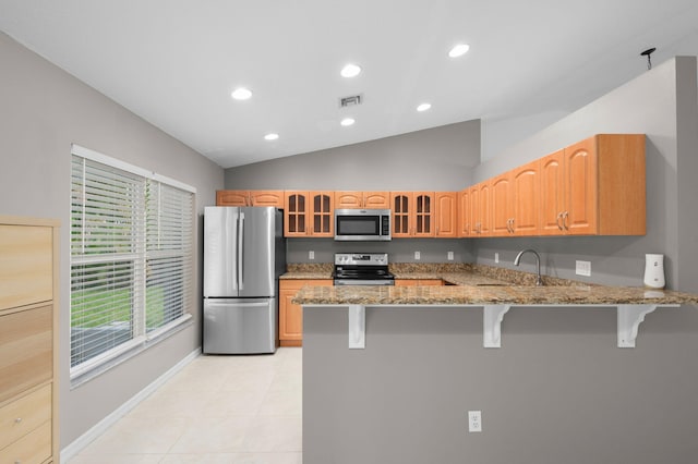 924 SW Abingdon Ave, Port Saint Lucie, FL 34953 - kitchen with stainless steel appliances, a kitchen breakfast bar, lofted ceiling, glass insert cabinets, and light stone countertops
