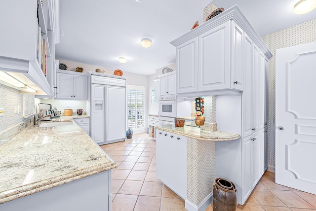 2160 Ibis Isle Rd Unit 9, Palm Beach, FL 33480 - kitchen with oven, paneled built in fridge, a sink, wallpapered walls, and light tile patterned floors