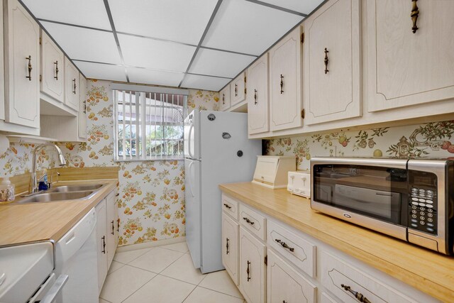 1250 Club Dr W Unit C, Delray Beach, FL 33445 - kitchen featuring wallpapered walls, a sink, white appliances, baseboards, and light tile patterned floors