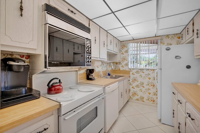 1250 Club Dr W Unit C, Delray Beach, FL 33445 - kitchen featuring wallpapered walls, white appliances, a sink, light tile patterned flooring, and baseboards