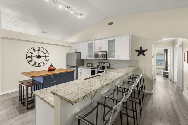 4312 SW Elaine Ct, Port Saint Lucie, FL 34953 - kitchen with appliances with stainless steel finishes, arched walkways, lofted ceiling, a breakfast bar, and wood counters