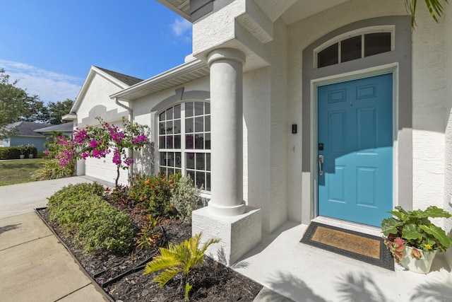 4312 SW Elaine Ct, Port Saint Lucie, FL 34953 - view of exterior entry featuring stucco siding, an attached garage, and concrete driveway