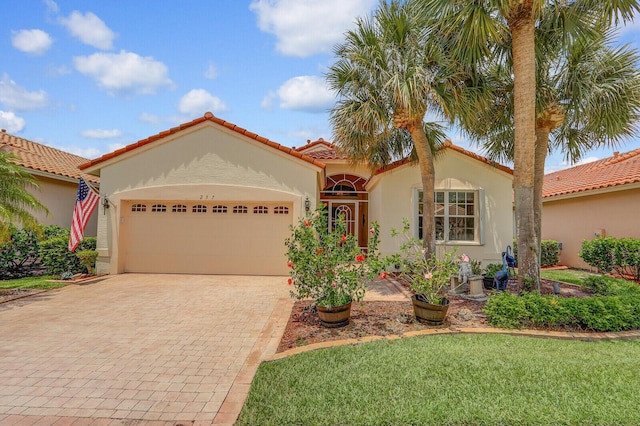 257 NW Toscane Trl, Port Saint Lucie, FL 34986 - mediterranean / spanish-style house with a garage, decorative driveway, stucco siding, a tile roof, and a front yard