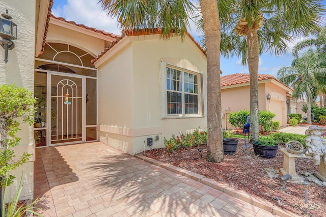 257 NW Toscane Trl, Port Saint Lucie, FL 34986 - view of exterior entry with crawl space, a tile roof, stucco siding, and an attached garage