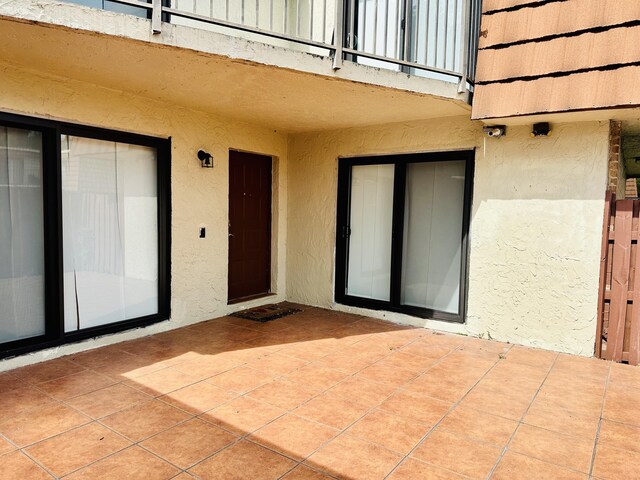 11887 SW 13th Ct, Davie, FL 33325 - view of exterior entry with stucco siding, a patio, and a security system