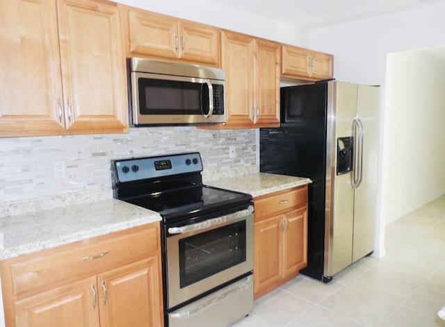 614 SW Jeanne St, Port Saint Lucie, FL 34953 - kitchen featuring appliances with stainless steel finishes, decorative backsplash, light stone countertops, and light tile patterned floors