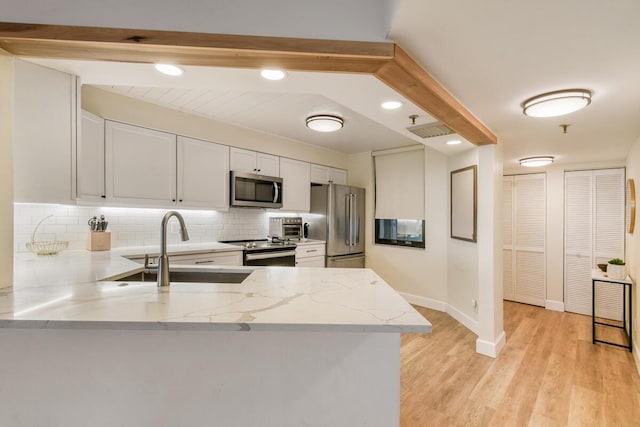9650 S Ocean Dr Unit 1604, Jensen Beach, FL 34957 - kitchen with stainless steel appliances, a sink, a peninsula, backsplash, and light stone counters