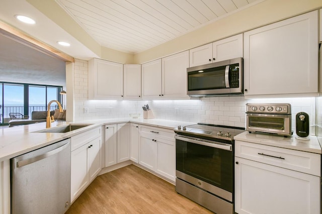 9650 S Ocean Dr Unit 1604, Jensen Beach, FL 34957 - kitchen with stainless steel appliances, a sink, decorative backsplash, white cabinetry, and light wood-type flooring