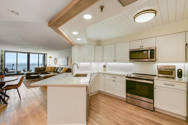 9650 S Ocean Dr Unit 1604, Jensen Beach, FL 34957 - kitchen featuring stainless steel appliances, a peninsula, backsplash, floor to ceiling windows, and light wood-type flooring