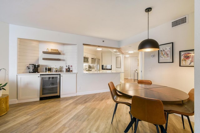 9650 S Ocean Dr Unit 1604, Jensen Beach, FL 34957 - dining area with wine cooler, light wood-style floors, a dry bar, and baseboards
