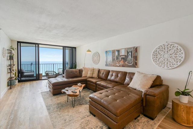 9650 S Ocean Dr Unit 1604, Jensen Beach, FL 34957 - living room featuring light wood-type flooring, a wall of windows, a water view, and baseboards