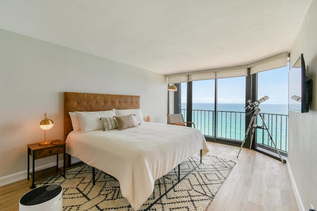 9650 S Ocean Dr Unit 1604, Jensen Beach, FL 34957 - bedroom featuring access to exterior, light wood-style flooring, floor to ceiling windows, and baseboards