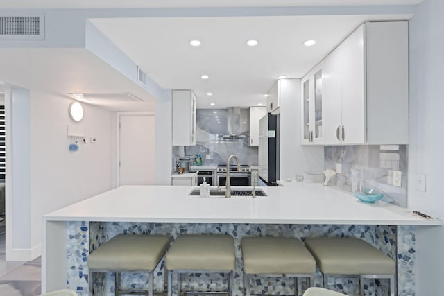 12 Royal Palm Way Unit 605, Boca Raton, FL 33432 - kitchen with a sink, a peninsula, decorative backsplash, white cabinetry, and a kitchen breakfast bar