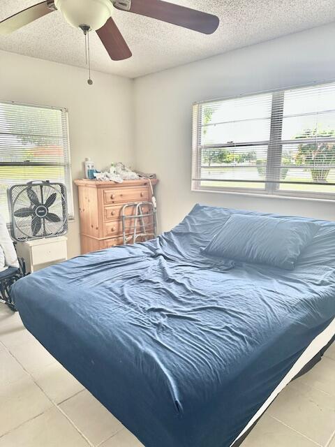 130 Brighton D, Boca Raton, FL 33434 - tiled bedroom featuring a textured ceiling and ceiling fan