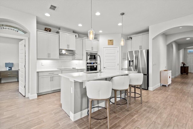 17936 Adrift Rd, Winter Garden, FL 34787 - kitchen featuring stainless steel appliances, under cabinet range hood, light countertops, a sink, and light wood-style floors
