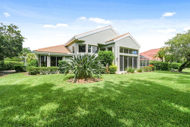 13312 NW Maplewood Rd, Palm City, FL 34990 - rear view of property featuring a sunroom, a tiled roof, a yard, and stucco siding