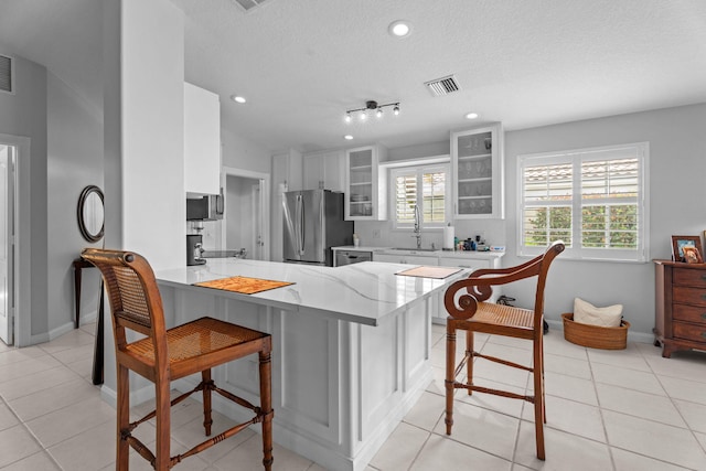 649 Hudson Bay Dr, Palm Beach Gardens, FL 33410 - kitchen with stainless steel appliances, a peninsula, a breakfast bar, glass insert cabinets, and a textured ceiling