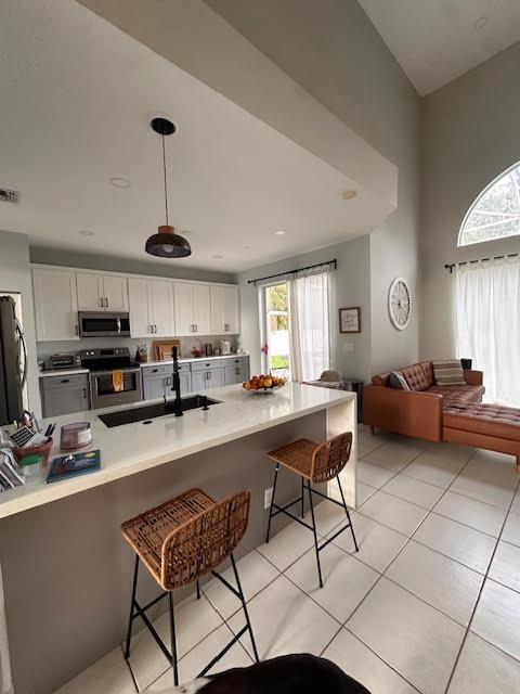 9202 Olmstead Dr, Lake Worth, FL 33467 - kitchen with stainless steel appliances, a kitchen bar, white cabinetry, and a peninsula