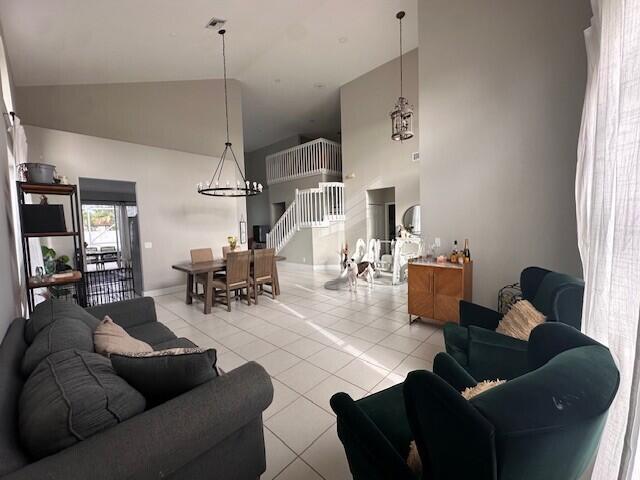9202 Olmstead Dr, Lake Worth, FL 33467 - living room featuring light tile patterned floors, a high ceiling, baseboards, a chandelier, and stairs