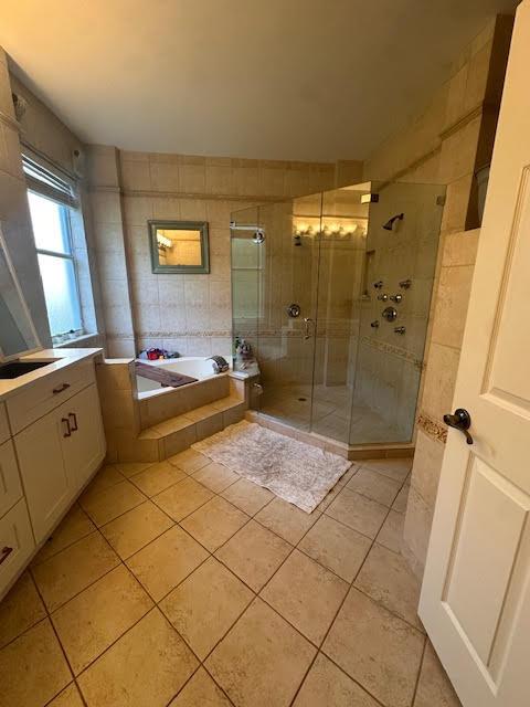 9202 Olmstead Dr, Lake Worth, FL 33467 - full bathroom with tile patterned floors, a garden tub, a stall shower, tile walls, and vanity