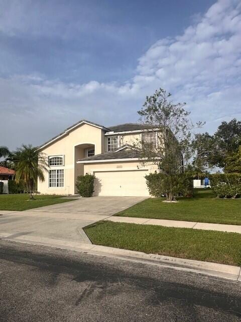 9202 Olmstead Dr, Lake Worth, FL 33467 - view of front of home with concrete driveway, a front yard, a garage, and stucco siding