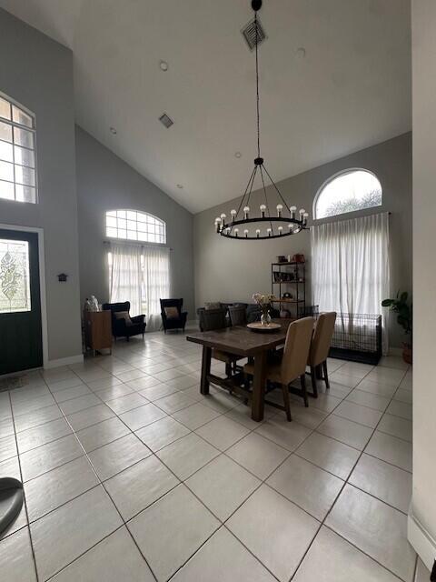 9202 Olmstead Dr, Lake Worth, FL 33467 - dining space with a chandelier, high vaulted ceiling, light tile patterned flooring, and baseboards