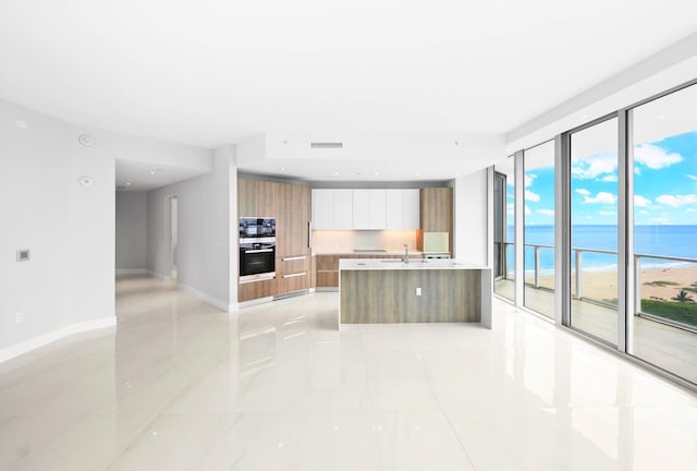 3100 N Ocean Dr Unit H-1708, Singer Island, FL 33404 - kitchen featuring modern cabinets, brown cabinets, light countertops, a water view, and a center island with sink