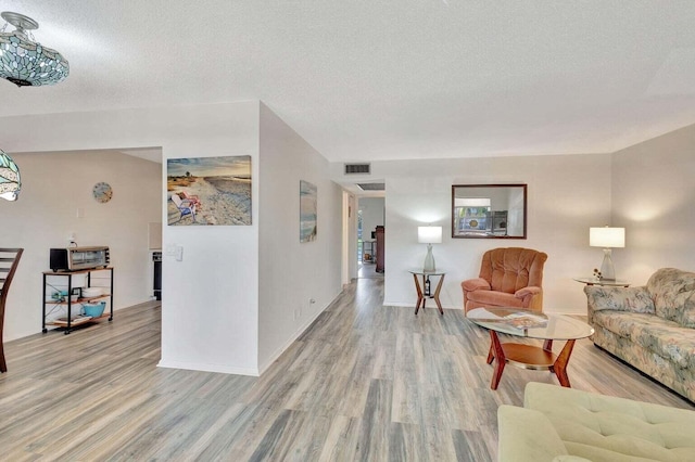 212 Somerset K, West Palm Beach, FL 33417 - living room with light wood-style flooring, a textured ceiling, and baseboards