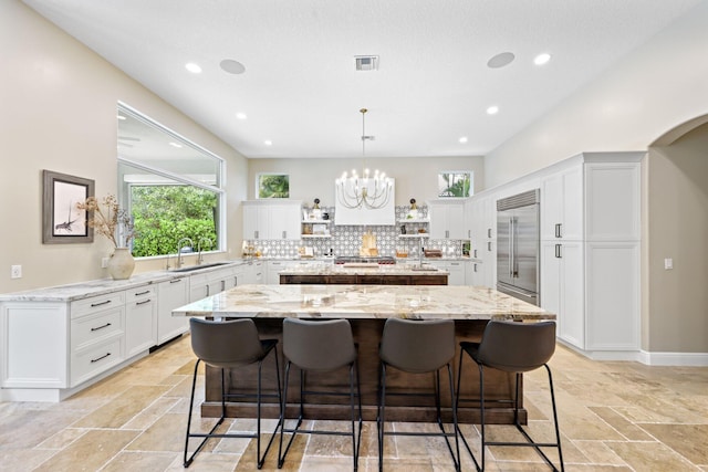7815 Fairway Ln, West Palm Beach, FL 33412 - kitchen featuring built in fridge, a kitchen island, a sink, stone tile flooring, and recessed lighting