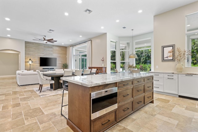 7815 Fairway Ln, West Palm Beach, FL 33412 - kitchen with a ceiling fan, a kitchen breakfast bar, recessed lighting, light stone counters, and white cabinets