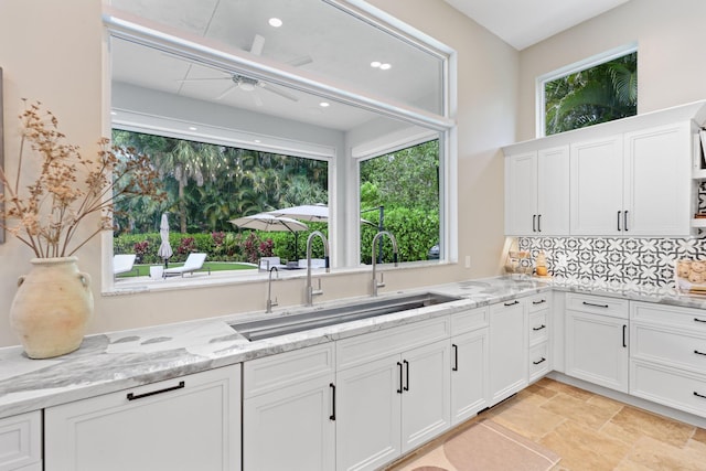 7815 Fairway Ln, West Palm Beach, FL 33412 - kitchen with a sink, a ceiling fan, white cabinetry, backsplash, and light stone counters
