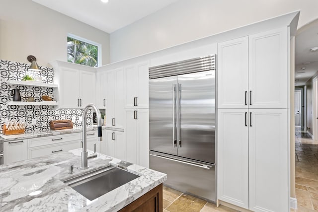 7815 Fairway Ln, West Palm Beach, FL 33412 - kitchen with built in refrigerator, a sink, open shelves, white cabinetry, and stone tile flooring