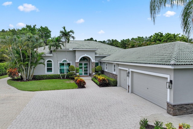 7815 Fairway Ln, West Palm Beach, FL 33412 - mediterranean / spanish home featuring stone siding, a garage, decorative driveway, stucco siding, and a front lawn