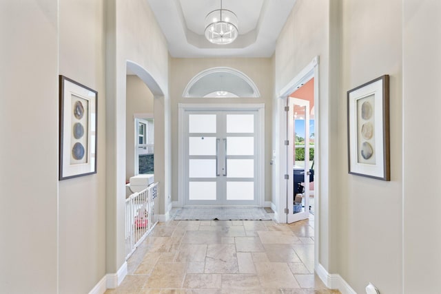 7815 Fairway Ln, West Palm Beach, FL 33412 - entryway featuring arched walkways, stone tile flooring, a chandelier, and baseboards
