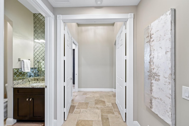 7815 Fairway Ln, West Palm Beach, FL 33412 - hallway featuring stone tile flooring, a sink, and baseboards