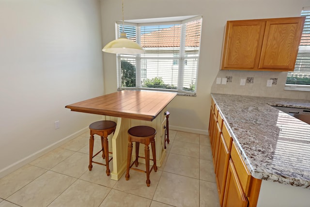 2365 55th Sq, Vero Beach, FL 32966 - kitchen featuring baseboards, light tile patterned floors, backsplash, light stone countertops, and a breakfast bar area