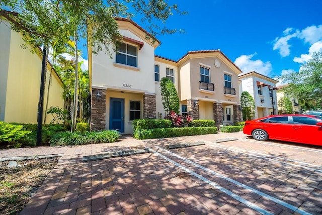 8328 Cocoplum Sound Ln, West Palm Beach, FL 33411 - townhome / multi-family property featuring stone siding, uncovered parking, stucco siding, and a tile roof