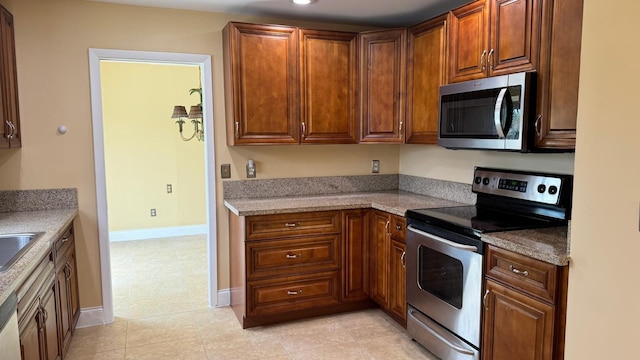 22544 Sawfish Ter, Boca Raton, FL 33428 - kitchen featuring appliances with stainless steel finishes, baseboards, and brown cabinets