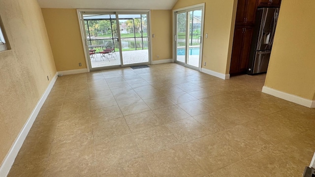 22544 Sawfish Ter, Boca Raton, FL 33428 - empty room with plenty of natural light, baseboards, light tile patterned flooring, and vaulted ceiling